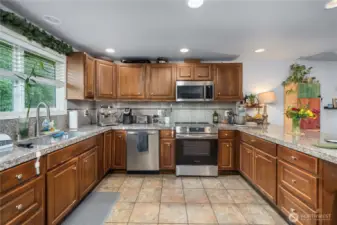 Unit 2 - Stainless Steel Appliances & Ample Storage  Well-appointed kitchen with ample cabinetry, stainless steel appliances, and a sleek electric range with overhead microwave. Tile backsplash adds easy-to-clean convenience.