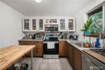 Unit 1 Spacious U-shaped layout offering ample counter space, overhead cabinetry, and a smooth-top electric range with built-in microwave above for convenience.