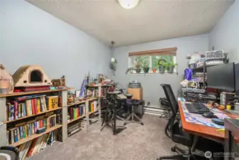 Unit 1 Versatile second bedroom with large window, neutral paint, and carpeted flooring — ideal for a home office, guest room, or hobby space.