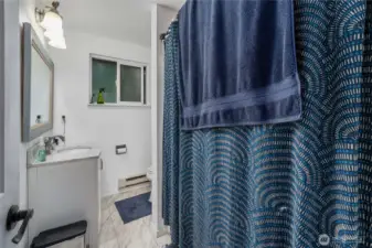 Unit 1 Bright and practical full bathroom featuring easy-care tile flooring, a shower/tub combo, and updated lighting. Neutral finishes make it simple to personalize, and a large window helps keep the space light and fresh.