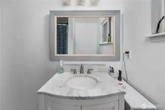 Unit 1 A modern vanity with a marble-style countertop provides storage and a clean, updated look. The oversized framed mirror and contemporary fixtures add a polished touch to the space.