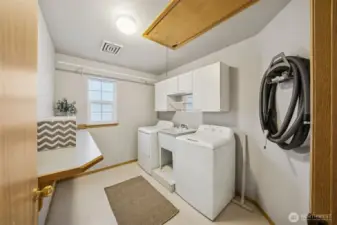 Upstairs laundry with utility sink, folding bar, cabinets and hanging rods