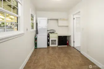Flex room between kitchen and garage includes stacked  laundry machines which stay with the house and utility sink.