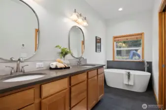 Primary bath with dual vanity, deep soaking tub and heated floors. Door on right leads to steam shower.