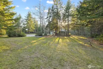 Westward views capture the soft glow of late-day sun streaming through the trees and across the lawn.  A quiet moment in nature where deer are known to wander at dusk.