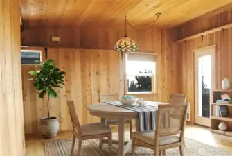 The upstairs dining room offers a warm, wood-lined space with plenty of room for gathering and enjoying the home’s coastal surroundings.