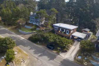 This aerial view showcases the home’s elevated setting surrounded by mature coastal trees and neighboring homes, just a short distance from the ocean.