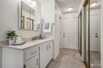 Primary suite's private sink & makeup counter, with the wall of closets to the right. Bathroom access to the left down the hall, and an exterior door to the backyard.