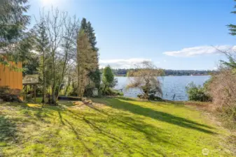 Gently sloping half-acre lot with a mid-century home in place, leveling out as it meets the water’s edge.