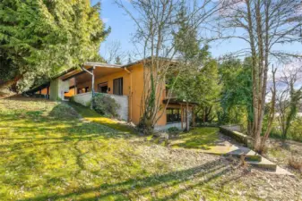 Gently sloping half-acre lot with a mid-century home in place, leveling out as it meets the water’s edge.