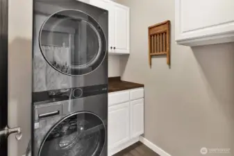 The laundry room includes the stacked washer and dryer plus a cabinet for storage and butcher block surface.