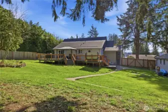 Living room steps out to deck with hot tub and HUGE, fully fenced yard with view of lake