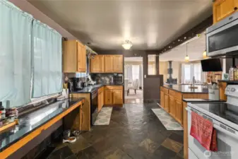 Updated kitchen featuring slate tile flooring, abundant counter space with slab countertops, a stylish tile backsplash, and a spacious central island designed for gathering & prep.