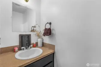 Small bathroom for guests in the hall has cabinet for storage as well as toilet and sink.