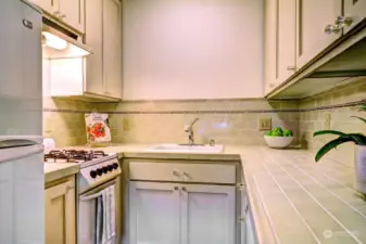 Well-appointed kitchen offers a gas range, tile countertops and backsplash