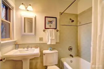 Remodeled bathroom with ceramic tile and  pedestal sink is equipped with an opening window