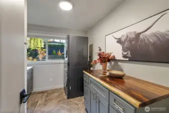 Updated laundry with plenty of cabinetry, storage and folding tables as well as front load stackable washer and dryer that stay with the home