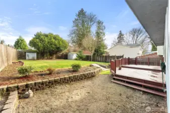 fully fenced backyard featuring mature landscaping, open lawn space, and two storage sheds. Ideal for gardening, play, pets, and outdoor gatherings.