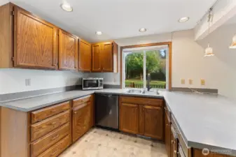 Spacious kitchen featuring abundant cabinetry, long countertops, and a large window overlooking the backyard. Plenty of workspace for cooking