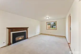 Bright and spacious living room with a large picture window and a cozy gas fireplace — offering a warm, welcoming atmosphere and direct views of the backyard.