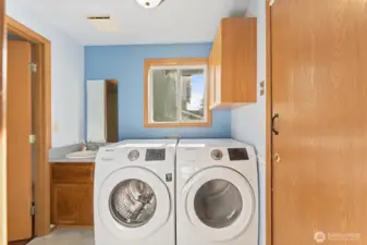 Well-appointed laundry room equipped with modern washer and dryer, built-in cabinetry,