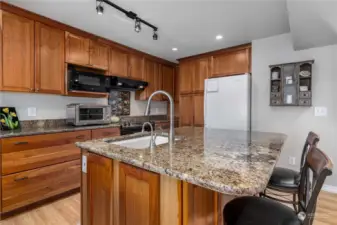 Granite counters / under mount sink with spray nozzle; instant hot water tap.  Cherry cabinets with deep lower soft close drawer, pull out corner cabinet   shelving, & sheet pan cabinet.  Pantry with pull out drawers and appliance garage.  Electric glass top stove & refrigerator (microwave goes with seller).