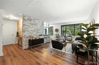 Another look at the gracious living area with gorgeous, engineered wood flooring, custom tile wall & lush, treed outlook for maximum privacy.