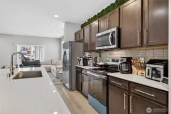 Gourmet kitchen showcasing sleek dark wood cabinetry, built-in microwave, and premium appliances