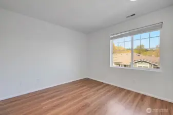 Bedroom 3 offers a bright and versatile space with fresh finishes and warm natural light. A large window frames neighborhood and treetop views, creating an inviting atmosphere for use as a bedroom, guest room, or home office. Clean lines and a modern palette make it an easy space to personalize.