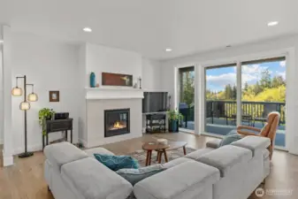 A modern gas fireplace anchors the airy living area, offering cozy ambiance while maintaining an open connection to the kitchen and dining space.