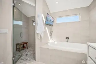 Separate tub and shower of primary suite. Yes, that is a mounted tv for you to enjoy while taking a bath!! This shower also has 'smart features' so that you can program the temperature and other settings you prefer.