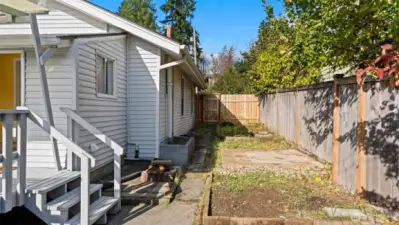 There’s so much happening in this side yard! You’ll find planting areas ready for your next garden project, a small paved spot where a hot tub once sat, and near the new wood fence that separates the front and back yards - established raspberry bushes already thriving. It’s a space full of potential and charm!