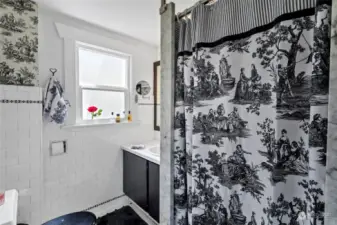 Main/Guest Bathroom with roomy walk-in shower and a chic black and white pallete. Linens storage shelf located just right of photo.