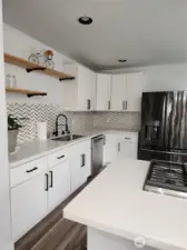 Plenty of cabinets for all your storage needs, refrigerator w/built-in Keurig and sleek  hardware on the cabinets.