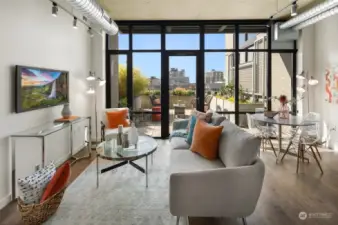 Welcome to Mosler Lofts' unit 515, where sunlight streams through the expansive floor-to-ceiling windows and door, leading to the unit's expansive private patio with views of the city skyline, creating a perfect indoor-outdoor flow.