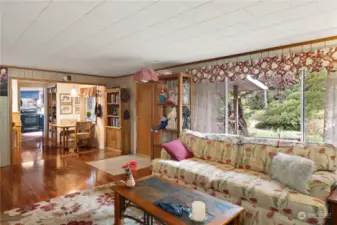 Living room has a large window. The breakfast nook is ahead to the right with the kitchen beyond.