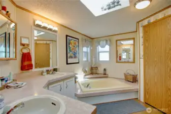 Bathroom off the main bedroom with oversized sunken tub and double sinks. Door to the right is storage closet and where the water heater is located.