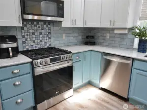 Kitchen w/ propane range and a stylish tile backsplash.