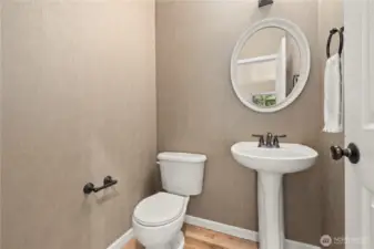 This stylish half bathroom is ideally located on the main floor of this Puyallup, WA home, just steps from both living rooms, the kitchen, and formal dining area. Featuring a classic pedestal sink, oil-rubbed bronze fixtures, and a round framed mirror, the space offers both function and charm. Neutral-toned wallpaper and hardwood floors add a refined touch. Perfect for guests, this powder room is a thoughtful and practical addition to the home’s well-planned layout in the heart of the LaGrande Station community.
