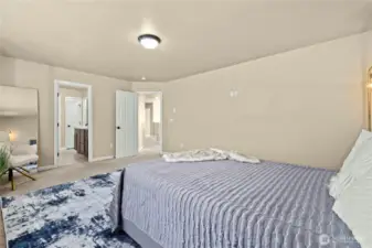 Spacious primary bedroom with walk-in closet and ensuite bathroom in Puyallup, WA    Step into this generously sized primary suite featuring plush carpeting, neutral tones, and dual access to a private ensuite bathroom and large walk-in closet. With direct hallway access and a serene greenbelt view, this upstairs retreat is located in the highly desirable LaGrande Station neighborhood of Puyallup, WA—just minutes from dining, parks, and the Washington State Fairgrounds.