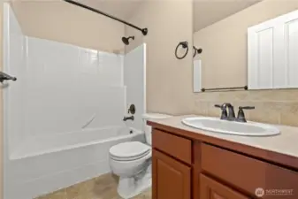 Located on the second floor of this beautiful home in Puyallup’s LaGrande Station community, this full bathroom offers functionality and classic design. It features a full shower/tub combo, brushed bronze fixtures, neutral tile flooring, and a spacious single-sink vanity with ample cabinet storage. Perfectly situated to serve the upstairs bedrooms, this bathroom provides comfort and convenience for family or guests in one of Puyallup, WA’s most desirable neighborhoods.
