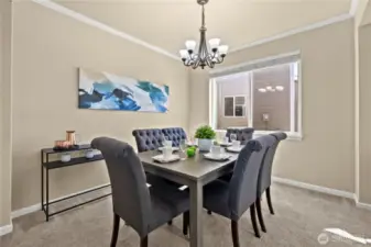 This elegant formal dining room in Puyallup, WA’s LaGrande Station community is the perfect space for hosting dinner parties or everyday meals in style. A large front-facing window fills the room with natural light, while crisp crown molding and a classic chandelier add a touch of sophistication. The soft neutral tones and plush carpet create a warm, inviting atmosphere that seamlessly connects to the home's open-concept layout. Whether you're gathering with friends or enjoying a quiet dinner, this space offers comfort, class, and the perfect setting in one of Puyallup’s most desirable neighborhoods.