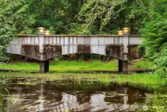 Upon entering the property, this solid moss covered cement bridge leads across the pond to the main home