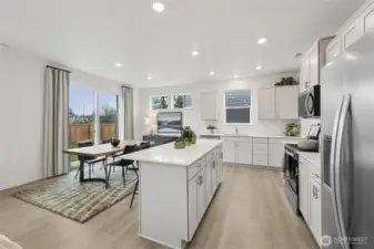 The heart of the home has an island kitchen, slab quartz countertops, full height tile backsplash, soft close cabinets, and plenty of light.  Picture for representational purposes only, colors and features may vary.