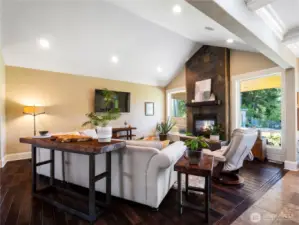 The living room area features beautiful wood floors, vaulted ceilings and a grand slate, indoor/outdoor gas fireplace.