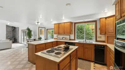 Enjoy a bright, open-concept kitchen featuring ample counter space, a center cooktop island, and modern can lighting—all seamlessly connected to the cozy family room with a wood-burning stove
