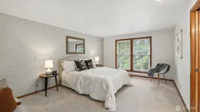The spacious primary bedroom features plush carpeting, large windows that invite natural light, and plenty of room to customize and create your perfect retreat.
