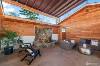 Gorgeous covered sitting area/breezeway walking from garage to side entrance with a tranquil fountain and beautiful stamped concrete