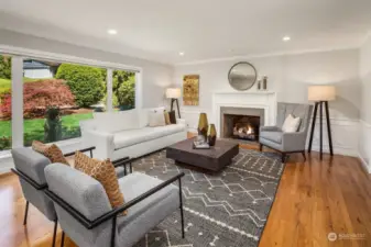 Generous living room is filled with light from the floor to ceiling windows overlooking the front yard. Gas fireplace, gorgeous hardwood floors, wainscoting and crown molding add to the allure.