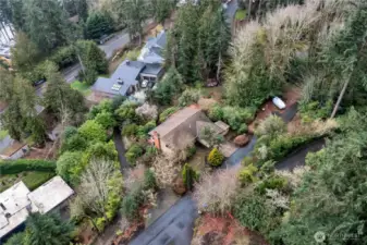 Drone view of home with brown roof on private road.